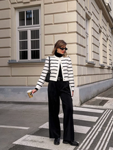 a lady wears a knitted cardigan with straight black pants and loafers